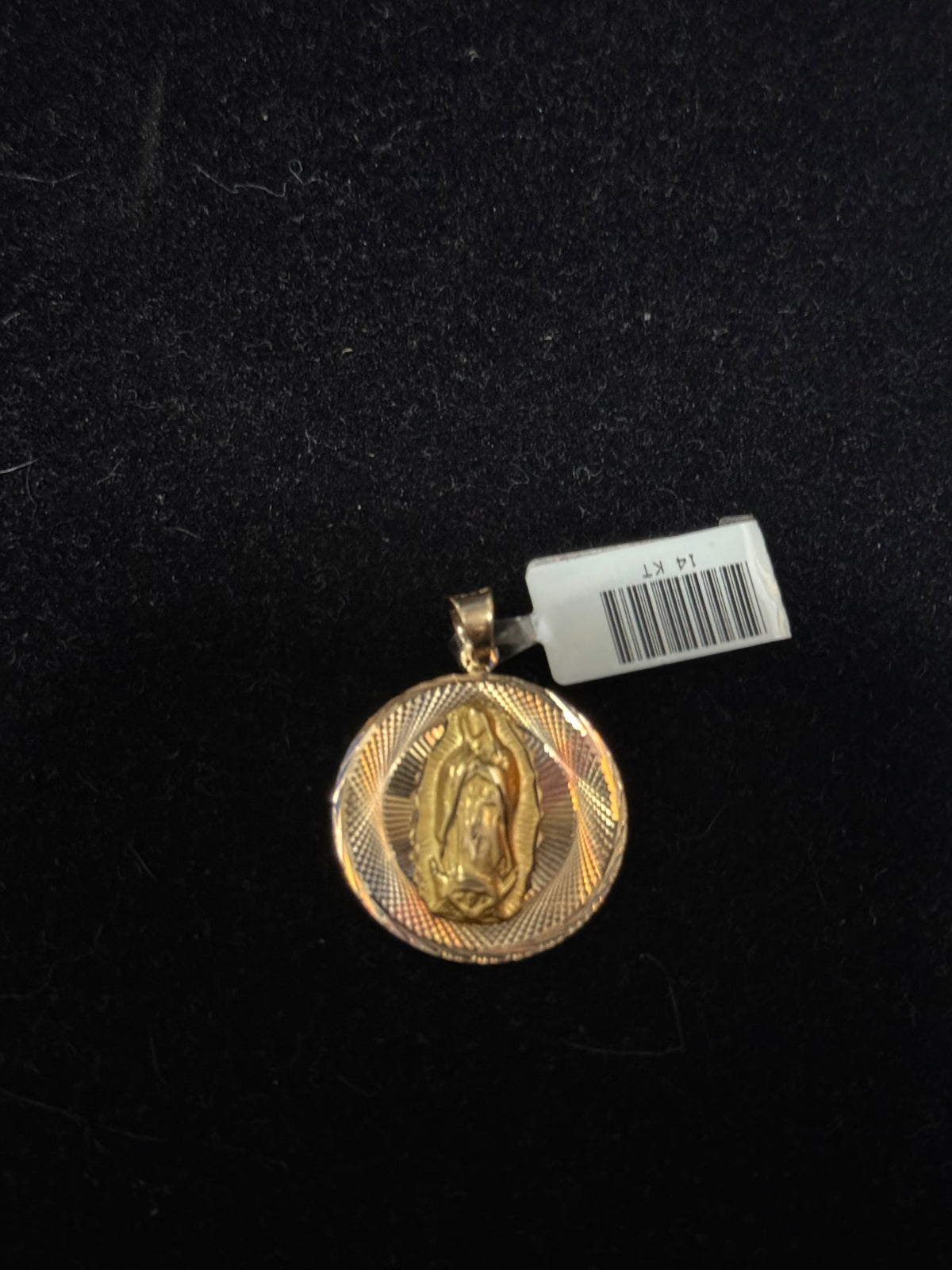 This image displays a striking gold-tone pendant featuring the image of the Virgin Mary. The circular pendant is elegantly designed with a detailed depiction of the virgin within a textured frame, enhancing its visual appeal.
