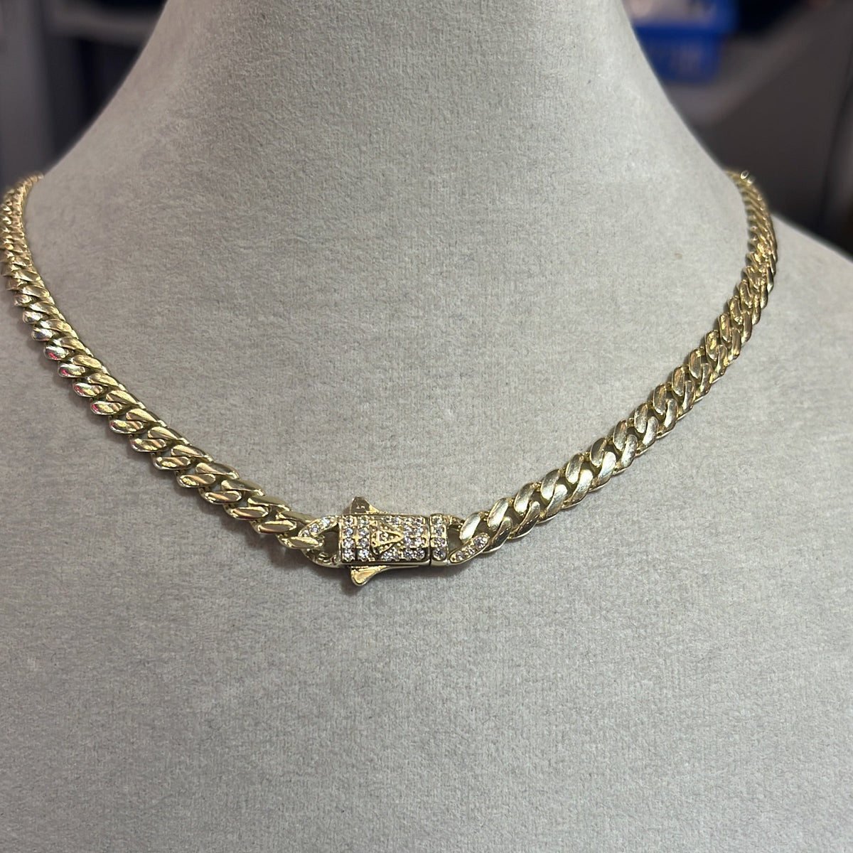 A gold-colored metal chain necklace displayed on a mannequin bust.